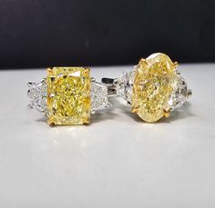 two yellow and white diamond rings sitting next to each other