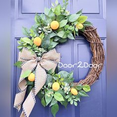 a grapefruit wreath with oranges and greenery hangs on a blue door