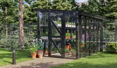 a small greenhouse in the middle of a yard with potted plants and flowers inside