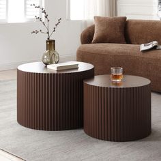 two coffee tables sitting on top of a carpeted floor next to a brown couch