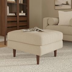 a living room scene with focus on the footstool and bookcase in the background