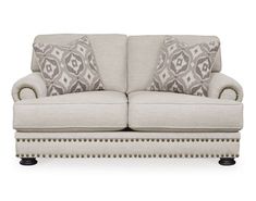 a couch with two pillows on top of it and some studded trim around the arms