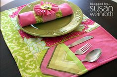 a place setting with pink and green napkins