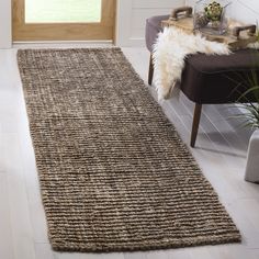 a large rug in the middle of a room with a chair and potted plant