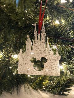 a christmas ornament hanging on a tree in front of a disney mouse head