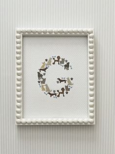 a white frame with some animals on it and a letter g in the middle that is made out of beads