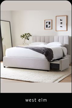 a white bed sitting on top of a wooden floor next to a mirror and rug