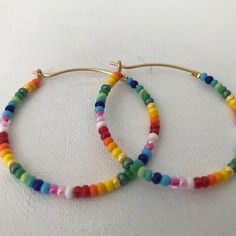 Colorful glass rainbow beads adorn a gold hoop earring. These lightweight earrings are so versatile. Everyday Rainbow Beaded Jewelry, Vibrant Rainbow Jewelry With Colorful Design, Colorful Bohemian Hoop Jewelry, Everyday Rainbow Round Bead Jewelry, Everyday Rainbow Jewelry With Round Beads, Multicolor Hoop Earrings With Ear Wire For Gifts, Multicolor Hoop Earrings With Ear Wire As A Gift, Everyday Multicolor Jewelry With Tiny Beads, Everyday Multicolor Beaded Jewelry