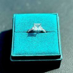 an engagement ring sits in a blue box