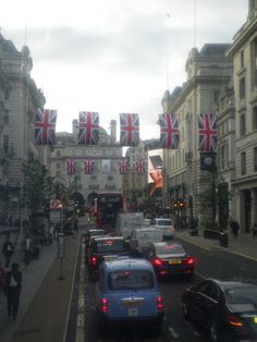 cars are driving down the street in front of buildings with union jack flags on them