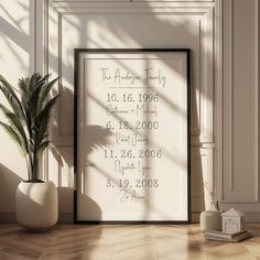 a white framed poster on the wall next to a potted plant and a clock