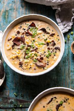 two bowls filled with soup on top of a wooden table next to silver spoons