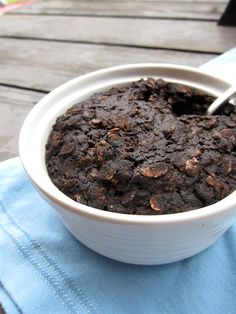 a white bowl filled with brownie pudding on top of a blue towel next to a wooden table