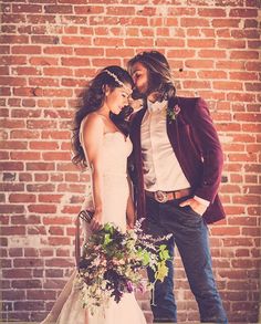 a man and woman standing next to each other in front of a brick wall