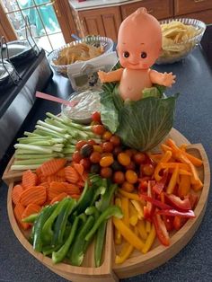 a baby doll sitting on top of a wooden plate filled with veggies and other foods