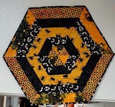 a yellow and black patchwork piece hanging on the wall next to a shelf filled with books