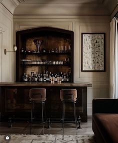 two bar stools sit in front of an open cabinet with liquor bottles on it