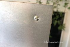 a laptop with a water drop sitting on top of it's back cover in front of a potted plant