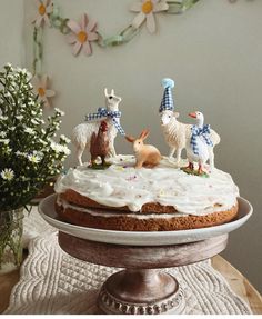 a cake with frosting and figurines of animals on it sitting on a table