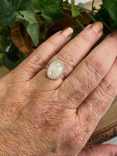 This cool, white Rainbow Moonstone gemstone ring reminds me of the puffy clouds that accent a Spring day. After a rain you can see the dark clouds turn to wisps of white with a faint rainbow glistening through. This stone is just that! As you look at the ring and turn it you will see subtle flashes of blue purple and maybe green. The lovely way the stone is nestled within the Sterling silver scalloped bezel setting gives this special piece a dainty yet bold look and feel. Designed in a timeless White Opal Celestial Ring, Celestial White Opal Ring, Celestial White Moonstone Ring With Halo, Celestial Style White Moonstone Ring With Halo, Celestial White Opal Jewelry, White Round Moonstone Ring Spiritual Style, White Oval Gemstone Jewelry, White Moonstone Ring With Oval Cabochon, White Moonstone Oval Cabochon Ring In Sterling Silver