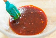 the sauce is being stirred in a glass bowl with a blue toothpick sticking out of it