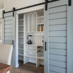 an open sliding door in a kitchen with white walls and wood flooring on the side