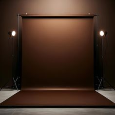 an empty photo studio with two lights on the wall and a brown backdrop behind it