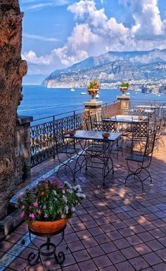 an outdoor patio with tables and chairs overlooking the ocean