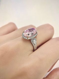 a woman's hand holding a pink and white diamond ring