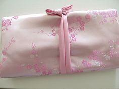 a pink wrapping paper with a bow on the top and flowers all over it, sitting on a table