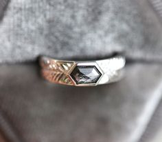 a close up of a ring on a person's finger with a grey sweater in the background