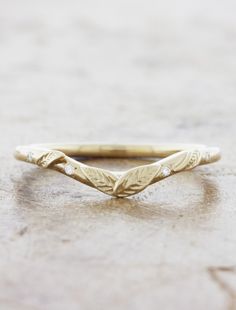 a gold wedding band with leaves on it