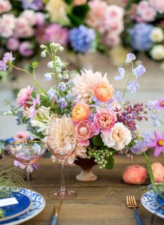 an arrangement of flowers in a vase on a table with plates and utensils