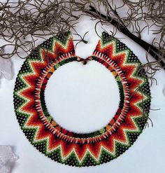 a colorful beaded necklace and earrings on top of snow covered ground next to twigs