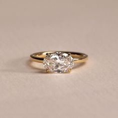 an engagement ring with a large diamond in the center on a plain surface, close - up