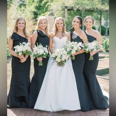 a group of women standing next to each other wearing dresses and holding bouquets in their hands