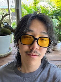 a man with glasses and a moustache on his face sitting at a table