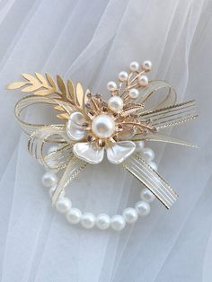 a bridal hair comb with pearls and gold leaves on white tulle fabric background