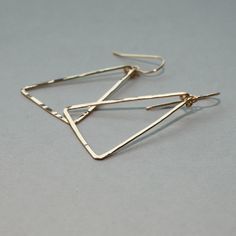 "Gorgeous and linear, these lightweight gold triangle earrings are hand shaped and forged to a glittering finish. Also available in rose gold filled and tarnish resistant sterling silver. These earrings are in it for the long haul : we only use high quality 14k gold fill, which (unlike gold plate) will never wear off or change color no matter how much you wear them. The silver we use is high quality and tarnish resistant. As long as you keep them clean they will be just as bright as the day they Minimalist Triangle Jewelry, Elegant Triangle Metal Earrings, Elegant Everyday Triangle Earrings, Elegant Triangle Everyday Jewelry, Triangle Metal Earrings For Gift, Triangle Gold Metal Earrings, Gold Triangle Metal Earrings, Gold Triangle Metal Jewelry, Gold Triangle Minimalist Earrings