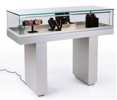 a white table topped with lots of purses under a glass display case on top of it