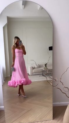 a woman in a pink dress is taking a selfie