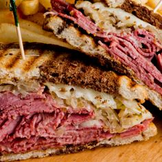 a roast beef sandwich cut in half with fries on the side