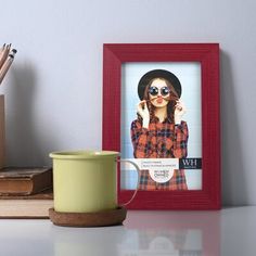 a coffee cup sitting on top of a desk next to a framed photo and pencils