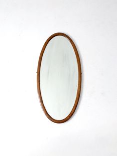 an oval wooden mirror hanging on the wall