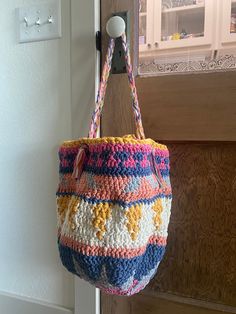 a crocheted bag hanging from a hook on a door handle with a window in the background