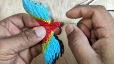 two hands are working on a beaded bird