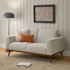 a living room scene with focus on the couch and book lying on the floor next to it