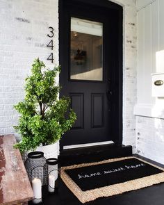 a black front door with a welcome mat and potted plant