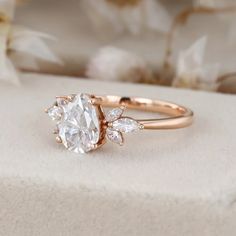 a rose gold engagement ring with an oval cut diamond surrounded by three pear shaped diamonds