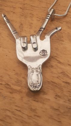 a silver pendant on a wooden table with two scissors in the shape of a cow's head